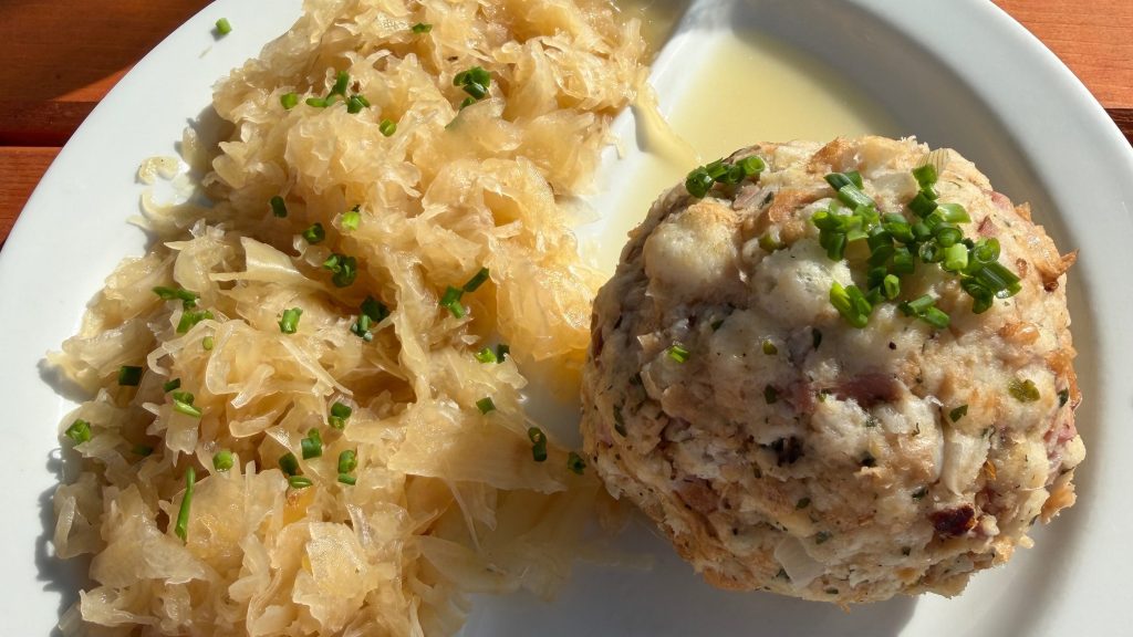 Traditional Tyrolean bread dumpling served with sauerkraut and fresh chives at an Alpine mountain hut in Austria. Copy